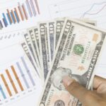 billetes-de-dolar-y-grafico-financiero-en-mano
