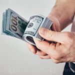 billetes-de-dolares-apilados-en-mano-masculina