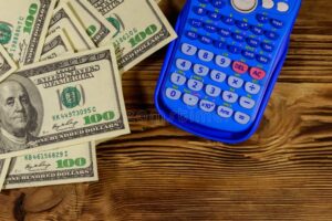 calculadora y billetes en mesa de madera