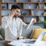 Cómo Consultar Cuánto Debo del Préstamo en Mi ANSES hombre-revisando-documentos-financieros-en-casa