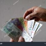 manos-sosteniendo-billetes-y-moneda-argentina