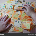 manos-sosteniendo-monedas-y-billetes-argentinos