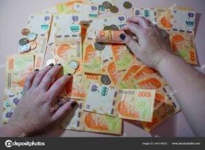 manos sosteniendo monedas y billetes argentinos