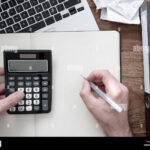 manos-usando-calculadora-y-billetes-encima