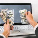 manos-usando-computadora-con-billetes-dolares