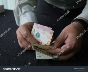 persona contando dinero en billetes argentinos