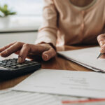 Cómo puedo hacer un control de gastos efectivo para ahorrar más persona-organizando-finanzas-con-calculadora-y-billetes