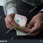 persona-pagando-factura-con-billetes-argentinos