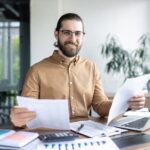 persona-revisando-documentos-con-computadora-abierta