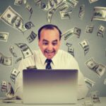 persona-usando-laptop-con-billetes-alrededor