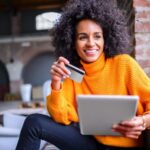 Dónde Solicitar Préstamos Online con Naranja Fácil y Seguro persona-usando-laptop-con-tarjeta-naranja